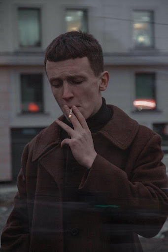 a man in a brown coat smoking